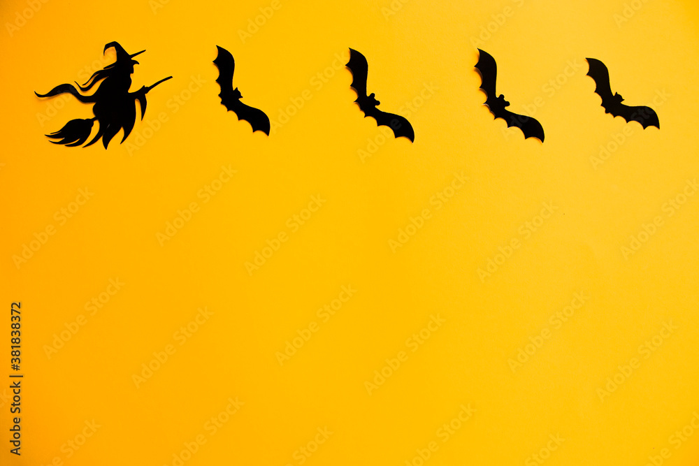 Silhouettes of black bats and witch on broom made of paper on orange background. Halloween greeting template with copy space. Flat lay for your design. Silhouettes of black bats and witch on broom made of paper on orange background. Halloween greeting template with copy space. Flat lay for your design.