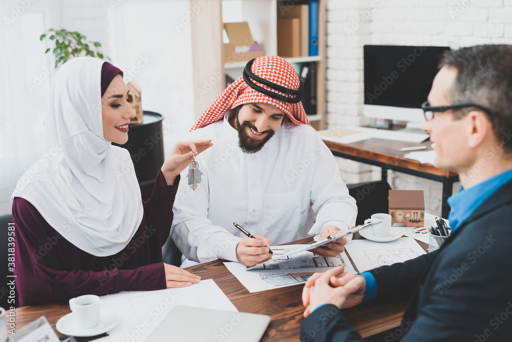 Fototapeta premium Arab woman holds key while an Arab signs contract.
