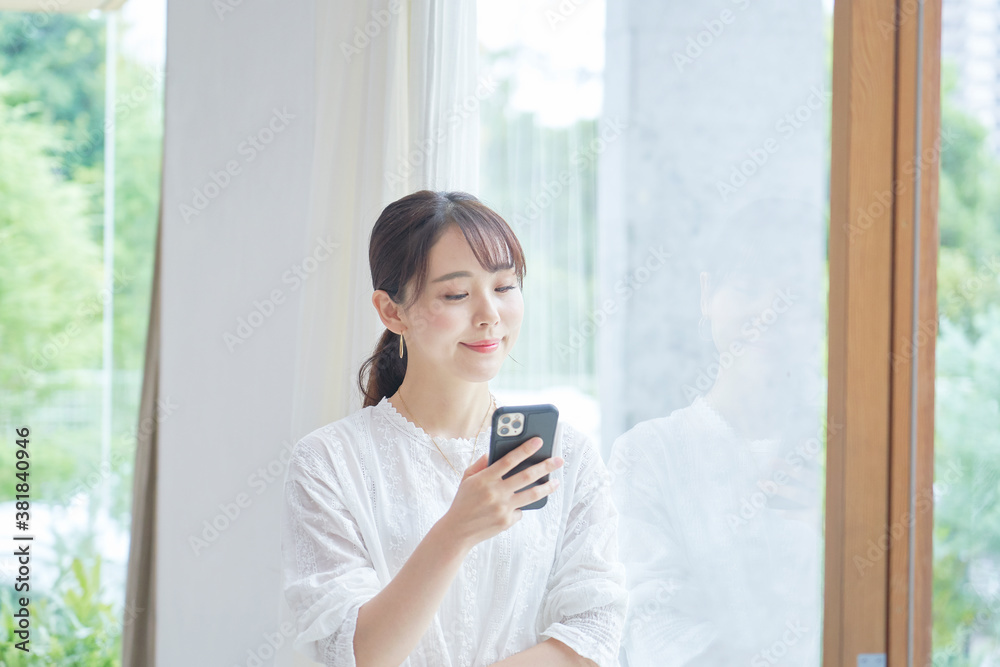 部屋でスマートフォンを使う女性 部屋でスマートフォンを使う女性