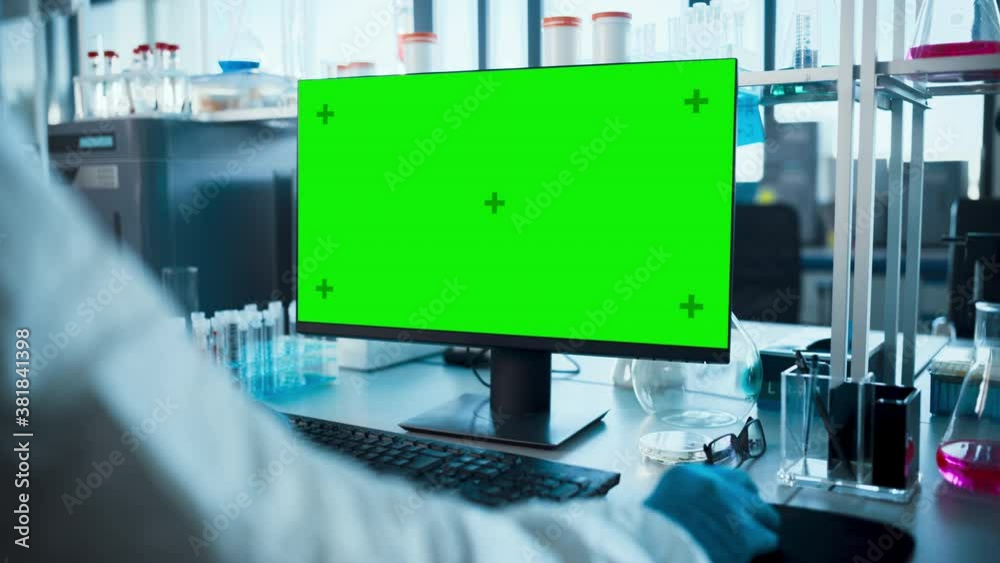 Advanced Laboratory: Microbiology Scientist Typing on Keyboard Works with Green Chroma Key Screen Computer Developing Vaccine, Drugs and Antibiotics. High-Tech Lab Shelf with Test Tubes, PIll Bottles