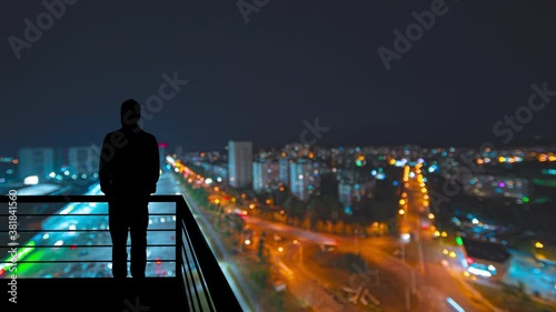 The man stands on the balcony on the night city background. hyperlapse