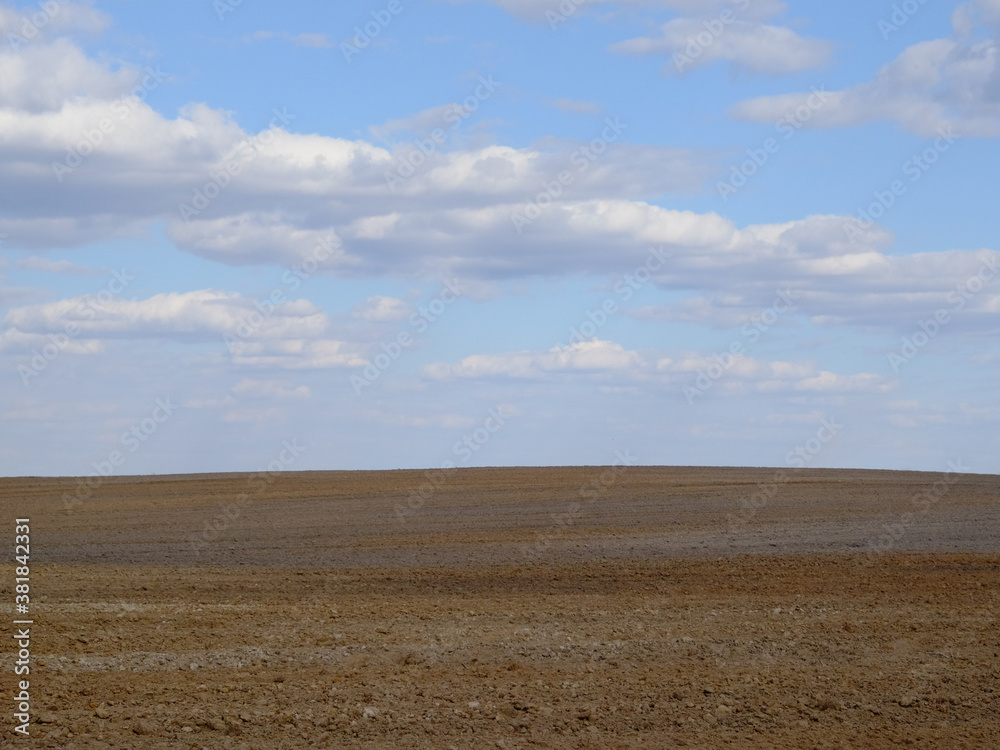 A plowed agricultural field. Blue sky over a farm field. A plowed agricultural field. Blue sky over a farm field.