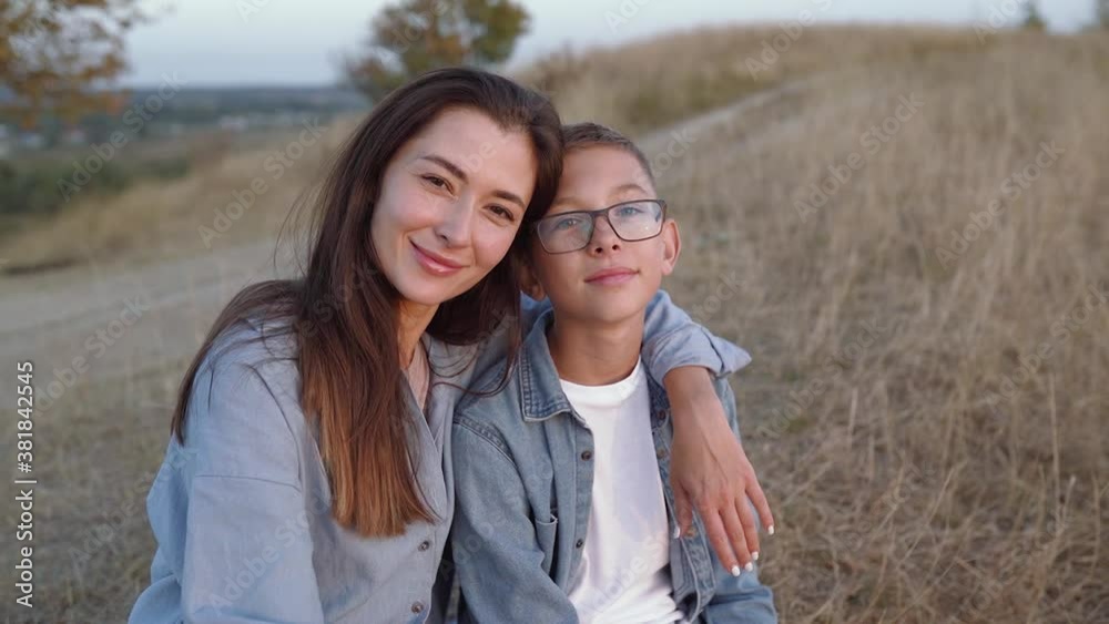 Mom and son sitting at the hills talking and looking to sunset