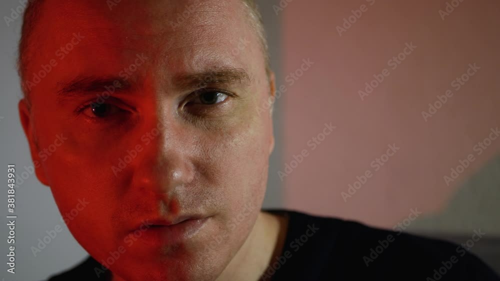 A young man with a serious look. Frowning man in red tones, evil smile A young man with a serious look. Frowning man in red tones, evil smile