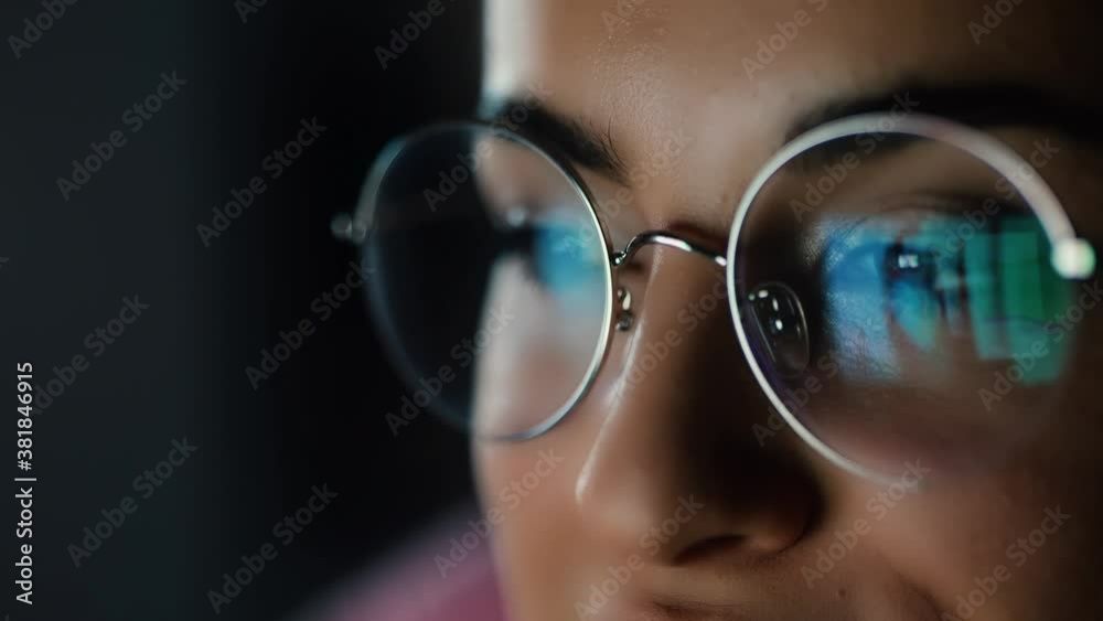 Young woman at home during quarantine. Close up girl's face looking on screen with its reflecting. Watching video or movie late at night.
