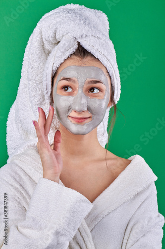 Portrait of young girl with skincare mask. Woman s wearing bathrobe and towel on her head. Health and spa treatment.