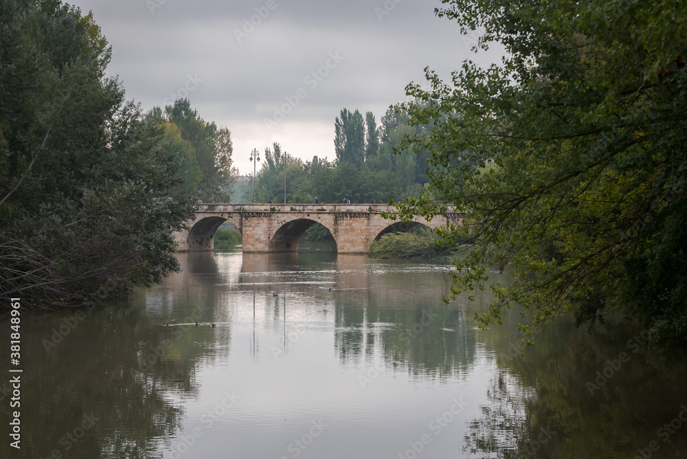 ashlar stone medieval bridge, puente mayor, crossing rio carrion, in autumn. Palencia, Spain.