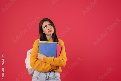 Image of unhappy beautiful student girl posing with exercise books