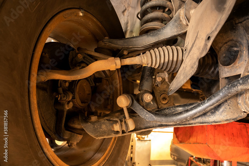 Slika na platnu Under old car closeup rear wheel axle suspension and exhaust chamber silencer muffler dirty fix repair in garage