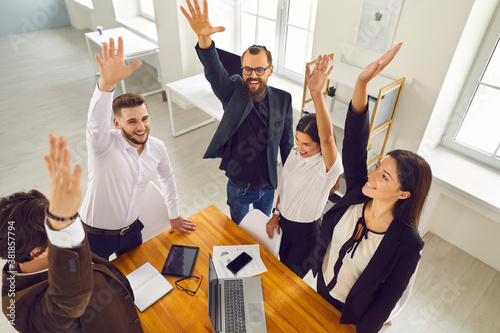 Tablou pe pânză Team of enthusiastic business people raising arms in work meeting celebrating su