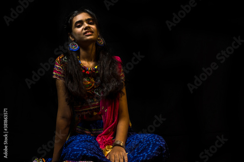 Indian girl in traditional chaniya choli for navratri with a fashionable hairstyle poses in studio on black background. Navratri is an Indian Festival and Chaniya choli its traditional costume photo