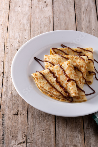 Sweet crepes with chocolate on wooden table. 	