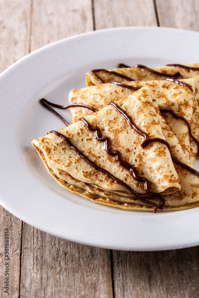 Sweet crepes with chocolate on wooden table. Sweet crepes with chocolate on wooden table.