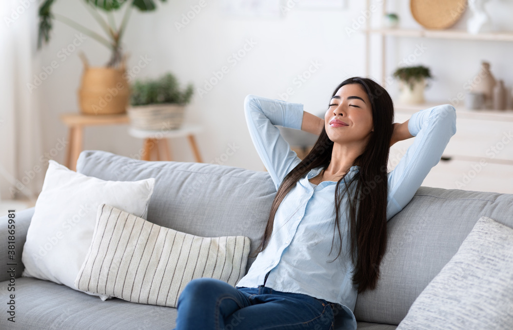 Home Comfort. Young Asian Lady Relaxing On Cozy Sofa In Living Room