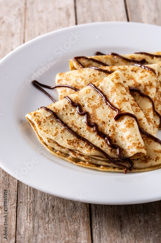 Sweet crepes with chocolate on wooden table.   © chandlervid85