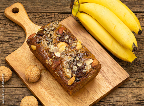 Banana bread on wooden plate with banana on wooden table background.