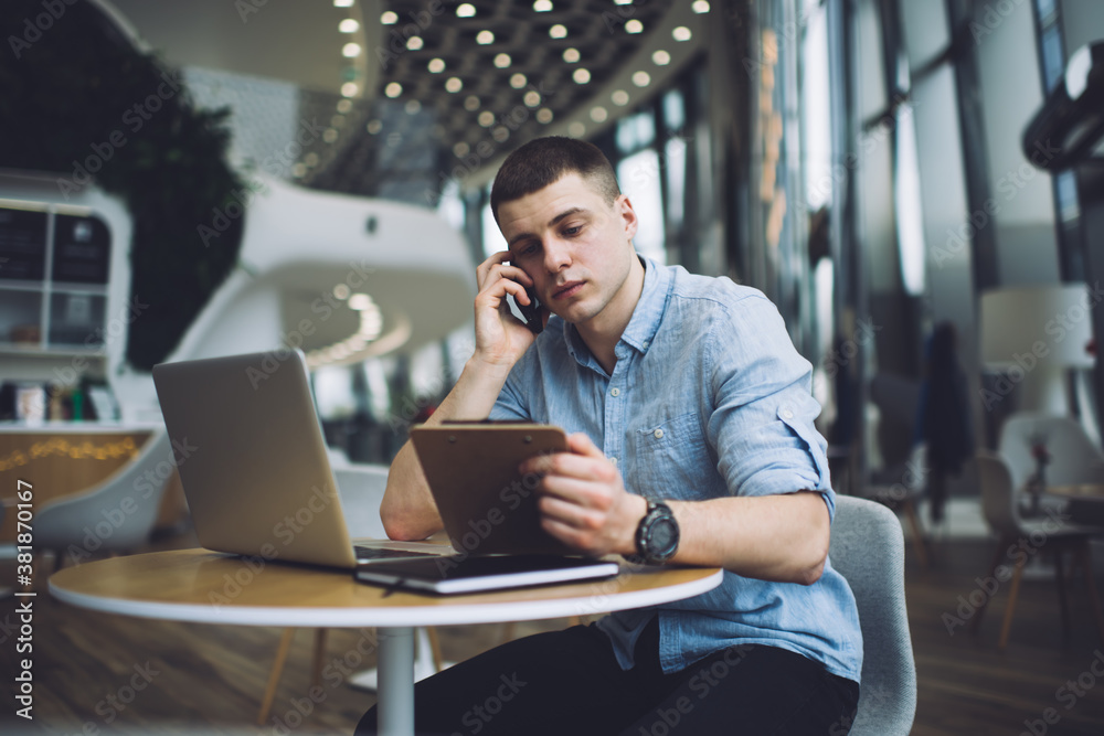 Pensive man talking on smartphone while working remotely Pensive man talking on smartphone while working remotely