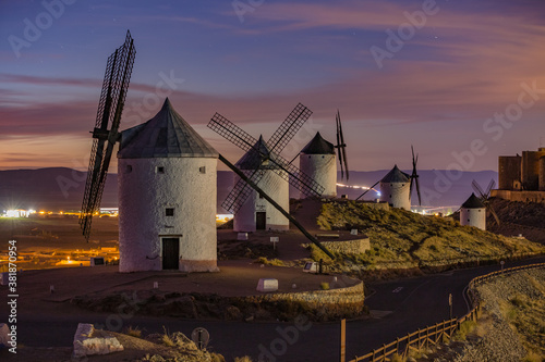 Beautiful white spanish windmill on the hill at fairy blue pink gold sunset near the castle in Consuegra, Toledo province, Spain