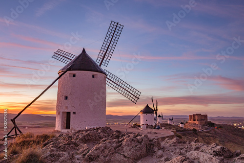 Beautiful white spanish windmill on the hill at fairy blue pink gold sunset near the castle in Consuegra, Toledo province, Spain