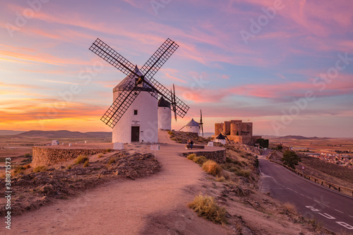 Beautiful white spanish windmill on the hill at fairy blue pink gold sunset near the castle in Consuegra, Toledo province, Spain photo