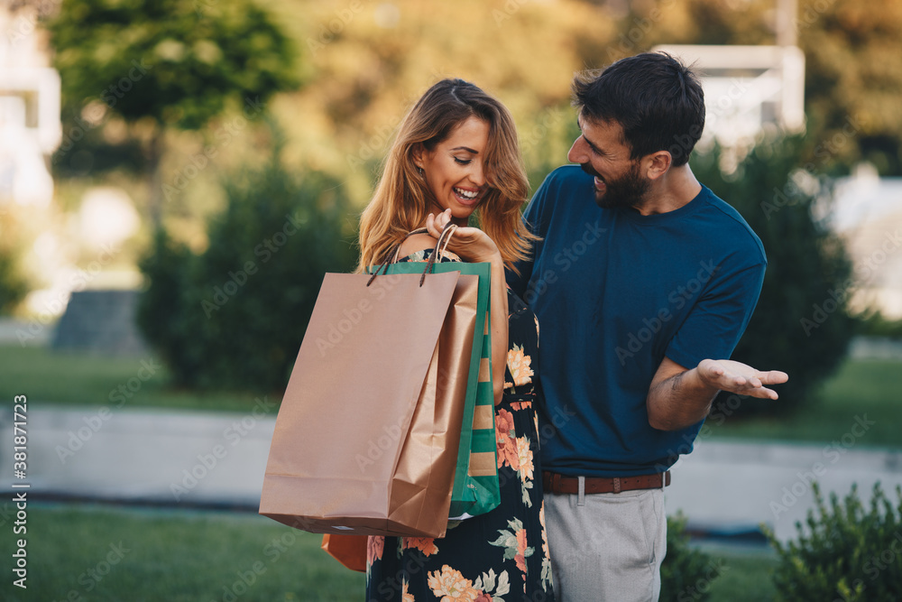 Naklejka premium Young attractive couple in love standing outdoors after shopping and hugging.