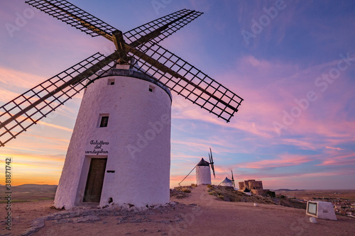 Beautiful white spanish windmill on the hill at fairy blue pink gold sunset near the castle in Consuegra, Toledo province, Spain