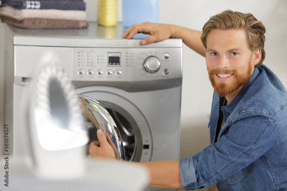 man is loading clothes or fabric into washing machine man is loading clothes or fabric into washing machine