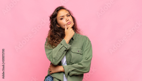 Foto looking serious, thoughtful and distrustful, with one arm crossed and hand on c