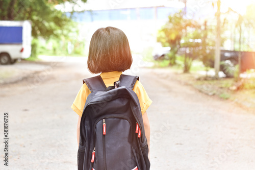 Schoolgirl pupil with backpack holding book in hand going to school. Education concept