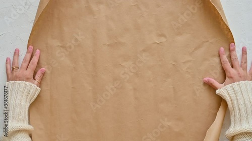 Female hands unroll gift wrapping paper. Christmas crafts. Top view.