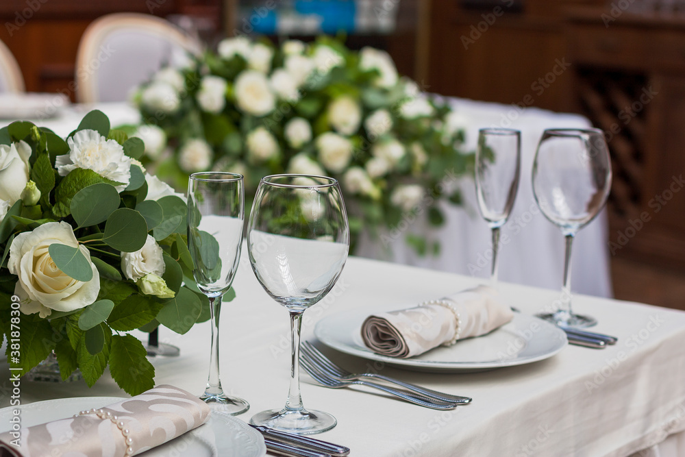 Fototapeta premium Glass wine glasses stand on the table against a background of flowers