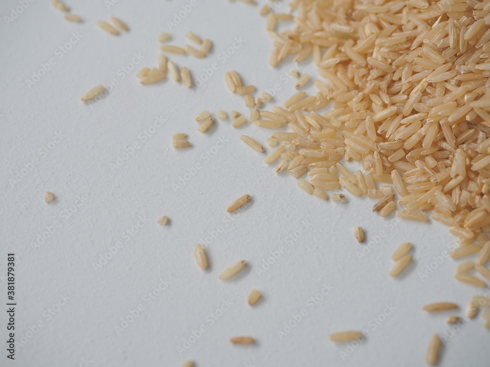 Obraz premium Coarse brown jasmine rice ( milled rice imperfectly cleaned, unpolished or half milled rice ) on white wooden background, Healthy food and diet concept.