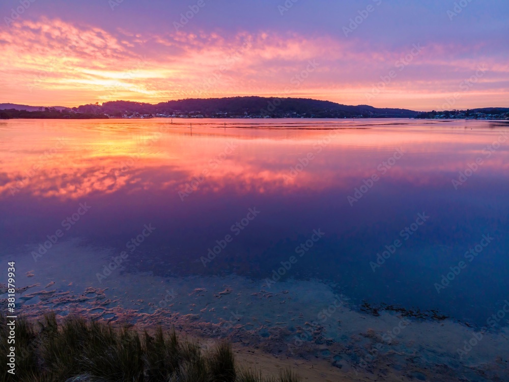 Pink reflections of sunrise with soft high cloud over the waterfront