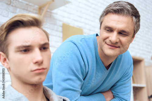 Father looks at his son and strive to cheer him up