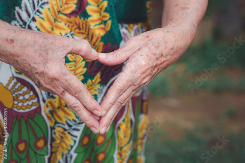 Close-up of hands senior woman showing making a heart shape with her hands and fingers. Concept of old people and love