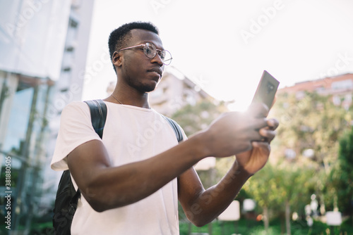 Confident young man browsing phone on sunny street