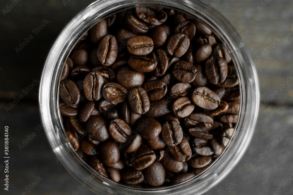 Fototapeta premium Fresh arabica coffee beans in a little jar on a wooden table. Fresh coffee beans.