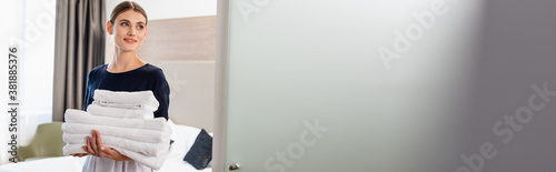 Konstfotografi horizontal image of young maid in apron looking at camera and holding clean towe