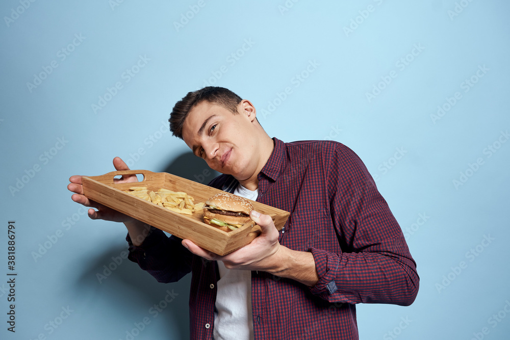 Man with wooden pallet fast food french fries hamburger hunger diet food blue background Man with wooden pallet fast food french fries hamburger hunger diet food blue background