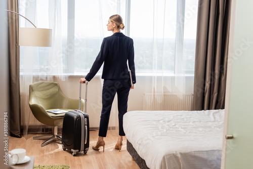 young businesswoman standing with laptop and suitcase in hotel room