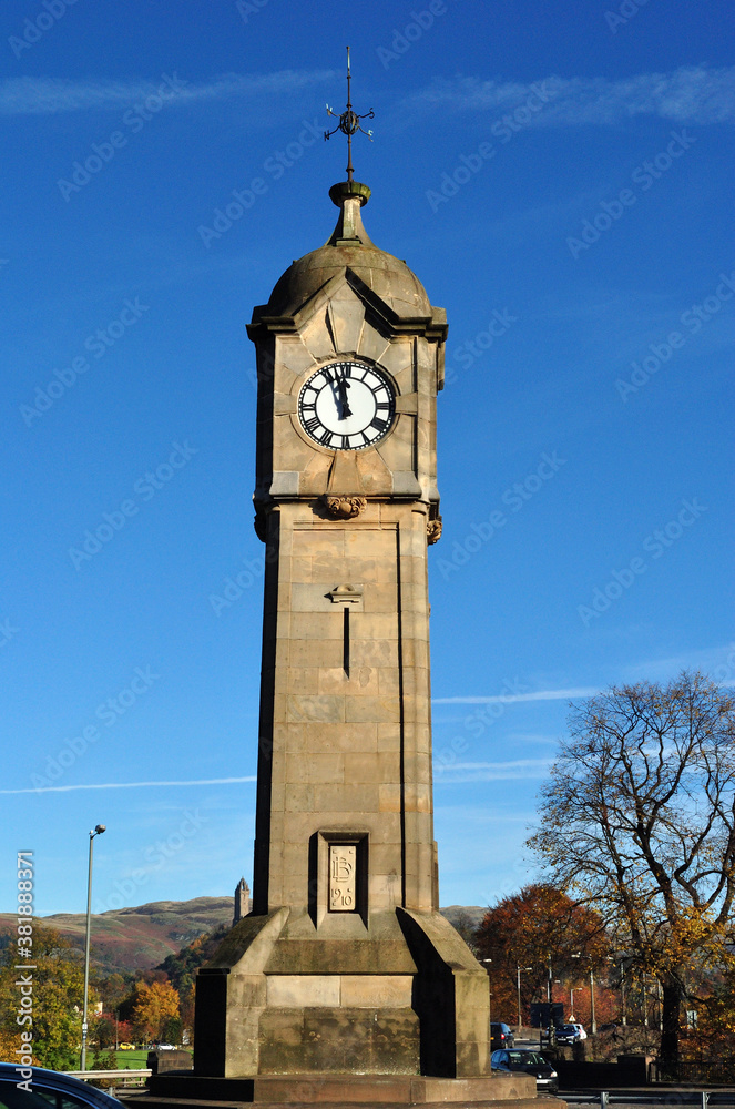 Isolated Stone Clock Tower & Tree with Golden Autumn Leaves against Blue Sky