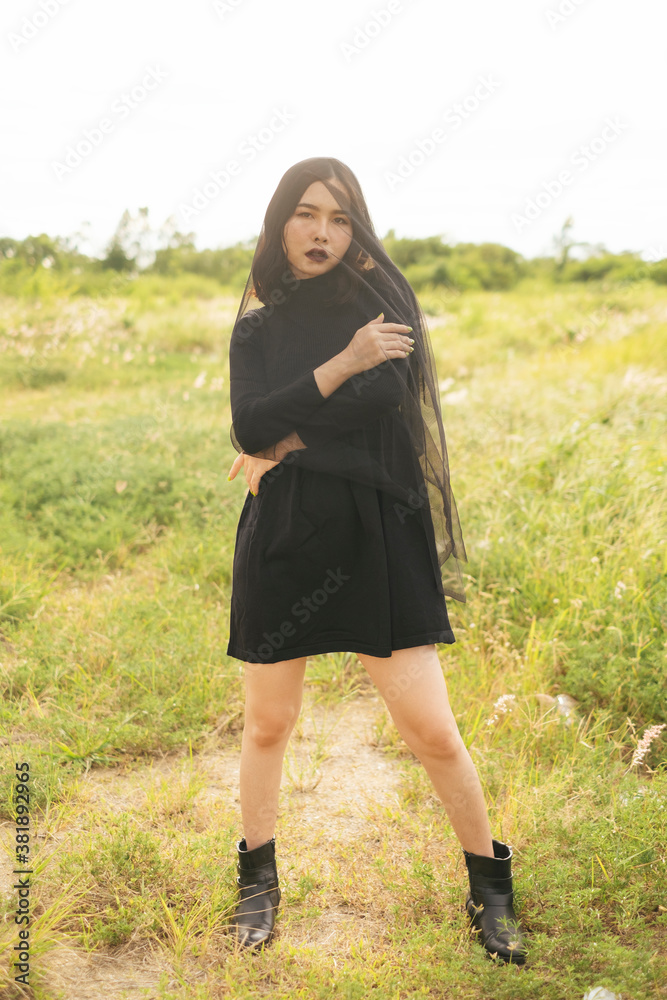 Portrait of asian witch with black veil on green meadow - halloween theme. Portrait of asian witch with black veil on green meadow - halloween theme.