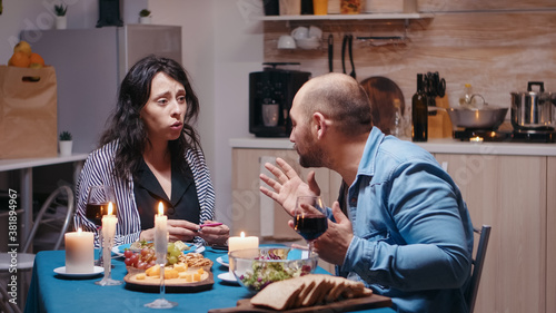 Happy pregnant woman dissapointed by husband during romantic dinner showing positive test. Unhappy  nervous  angry man fighting with wife  unwanted baby  frustrated for results.