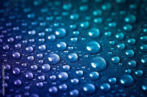 Lots of water droplets splattered on the shiny metallic texture. Blue-purple background color