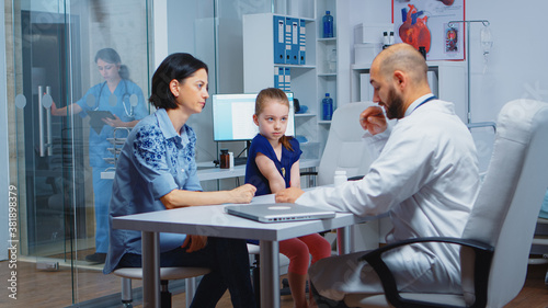 Doctor working on diagnostic examination for child health, talking and writing. Specialist in medicine providing health care services consultation diagnostic examination treatment in hospital cabinet
