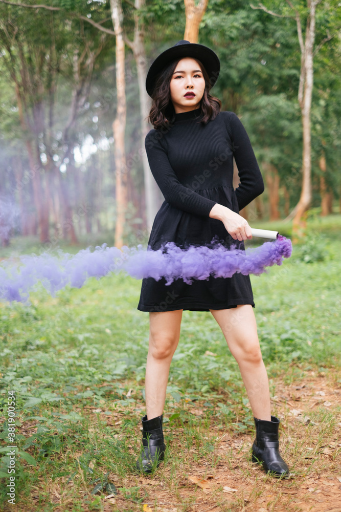 Portrait of asian black witch with purple smoke torch in deep forest - halloween theme. Portrait of asian black witch with purple smoke torch in deep forest - halloween theme.