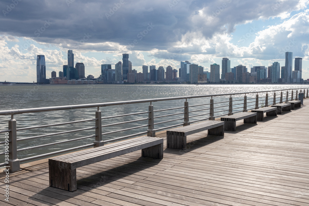 Row of Empty Benches on a Pier along the Hudson River in New York City with a view of the Jersey City Skyline