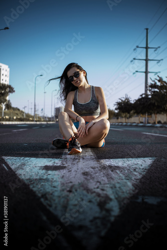 Young women in sport outfit sitting in the middle of highway