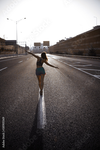 Yong woman balancing on the line of empty highway