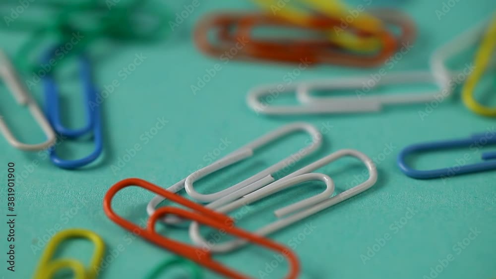 colored paper clips fall on the blue table. school supplies . paper clips close up colored paper clips fall on the blue table. school supplies . paper clips close up